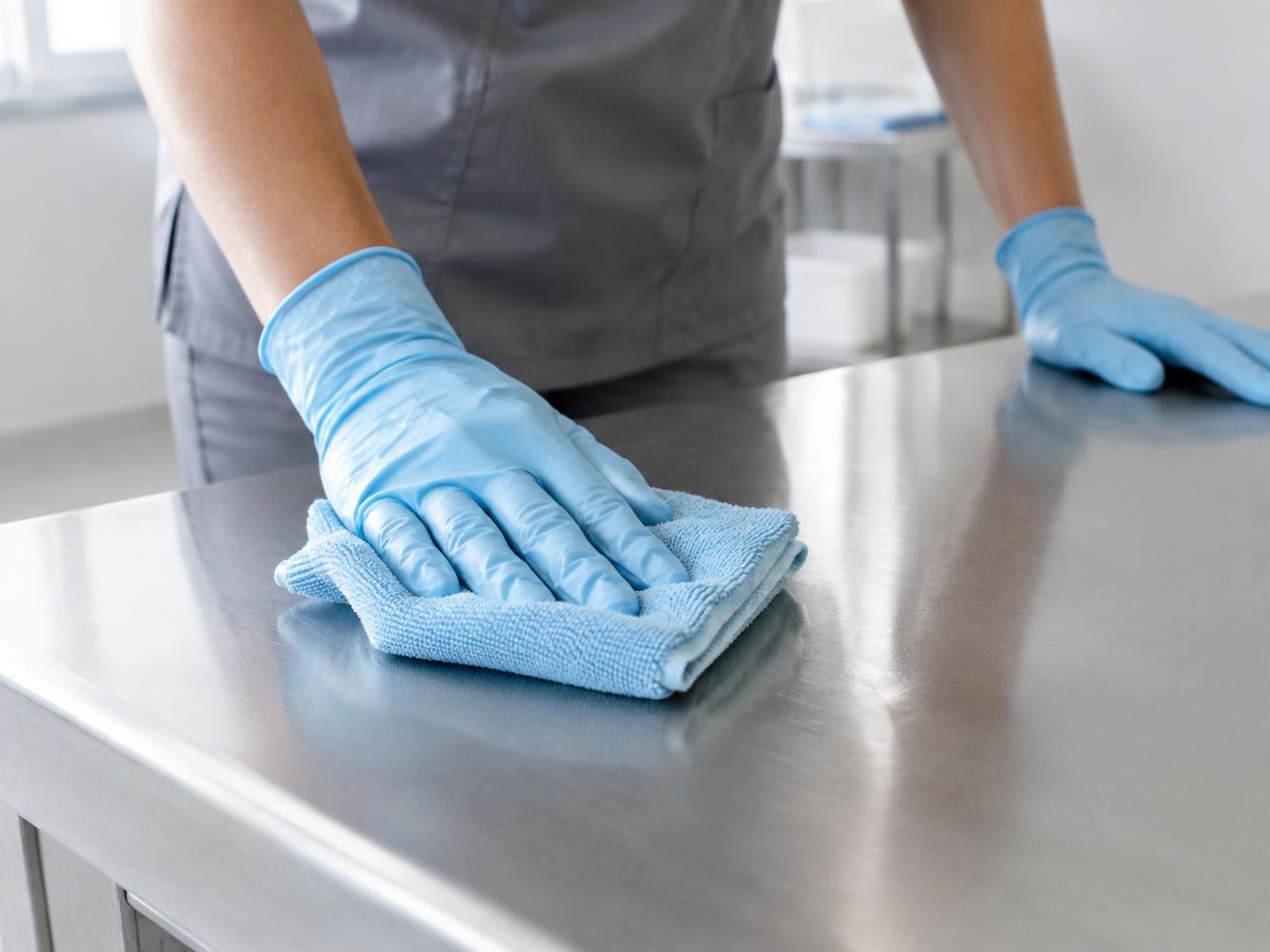 Gloved hands cleaning a steel surface